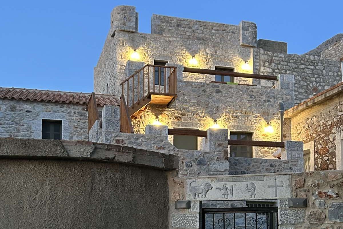Πέτρινη διώροφη κατοικία στο Καραβοστάσι Λακωνίας, φωτισμένη το σούρουπο